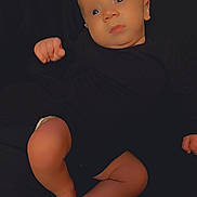 Xavion is registered to the contest to win money with this photo: baby, infant, newborn, child, portrait, lying_down, black_background, onesie, bare_legs, feet, hands, eyes, face, skin, closeup, cozy, looking_up, candid, soft_lighting, studio_style