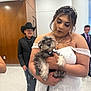 bride, dog, wedding, white_dress, lace, tuxedo, puppy, indoor, person, cowboy_hat, formal_wear, man, woman, holding, celebration, people, smiling, background, floor, wall