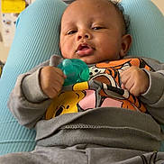 Josiah is registered to the contest to win money with this photo: baby, infant, pacifier, clothing, sweatshirt, person, face, hand, legs, indoor, home, furniture, sitting, child, cute, expression, relaxed, casual, background, shelf