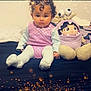 baby, bed, casual_clothing, child, comfort, cozy, curly_hair, cute, indoor, lighting_effect, plush_toy, portrait, purple_outfit, sitting, smiling, soft_toys, sparkles, toddler, toy, young_child