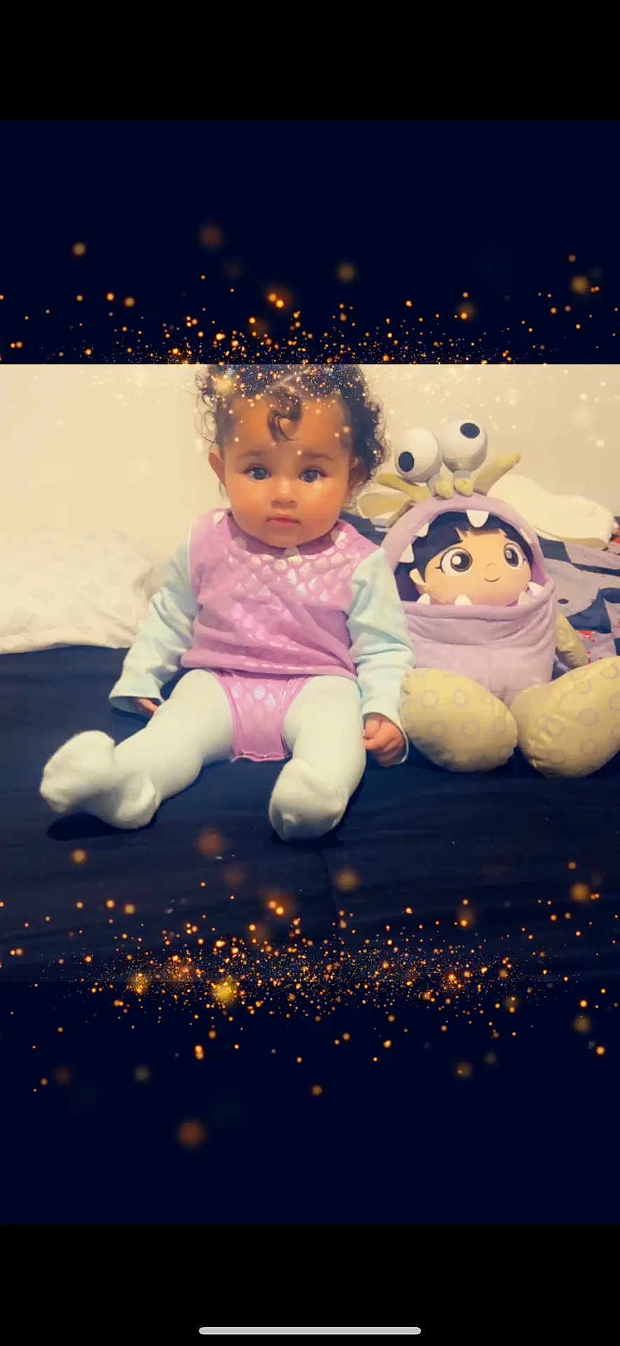 Azrique is registered to the contest to win money with this photo: baby, bed, child, cozy, curly_hair, cute, decorative_lights, face, home, indoor, person, plush, portrait, purple_clothing, sitting, smiling_toy, soft_toys, sparkle_effect, stuffed_toy, white_tights