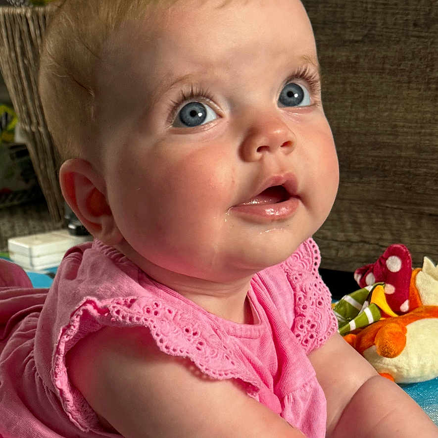 Daisy-Mai joined the competition — help win amazing prizes! baby, baby_girl, blue_eyes, child, colorful, curious, cute, drool, expression, face, floor, indoor, infant, mouisture, person, pink_dress, playmat, portrait, soft_toys, young