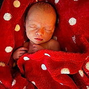 Kairo is registered to the contest to win money with this photo: newborn, baby, sleeping, blanket, red_blanket, polka_dots, infant, cute, peaceful, child, soft_texture, cozy, resting, wrapped, portrait, human, skin, hand, head, closed_eyes