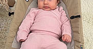 Serena is registered to the contest to win money with this photo: baby, child, pink_outfit, hair_bow, baby_seat, indoor, carpet, wooden_floor, curious_expression, cozy_clothing, wide_eyes, wild_hair, footwear, plush_socks, home_interior, furniture, decor, portrait, sitting, infant