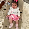 baby, child, pink_bow, smiling, baby_seat, white_shirt, pink_shorts, socks, carpet, wooden_table, indoor, cute, happy, infant, portrait, clothing, floor, home, person, seat