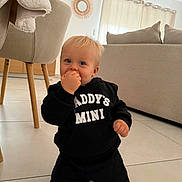 Elio a rejoint le concours — aidez-le/la à gagner de superbes lots ! toddler, child, baby, kneeling, hoodie, black_clothing, indoor, living_room, furniture, curtains, tile_floor, person, cute, blue_eyes, blond_hair, smiling, casual, modern_decor, cozy, home