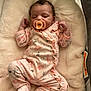 baby, newborn, sleeping, pacifier, onesie, pink_clothing, infant, soft_blanket, cute, peaceful, child, lying_down, plush, indoors, adorable, closed_eyes, cozy, small_hands, footed_pajamas, resting