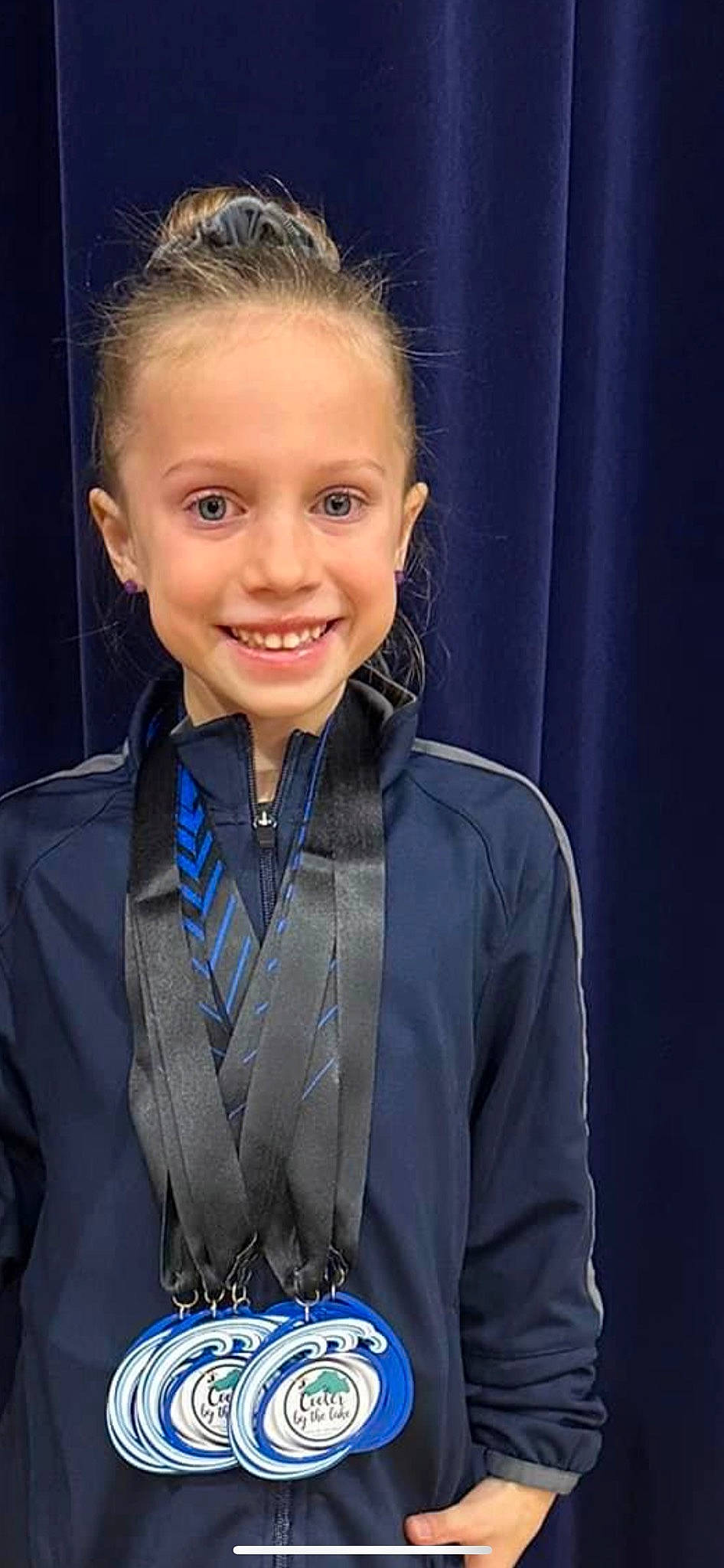Maisie is registered to the contest to win money with this photo: blazer, collar, curtain, electric_blue, event, fashion_accessory, flash_photography, formal_wear, gesture, hairstyle, happy, jewellery, joy, neck, official, person, school_uniform, sleeve, smile, toddler