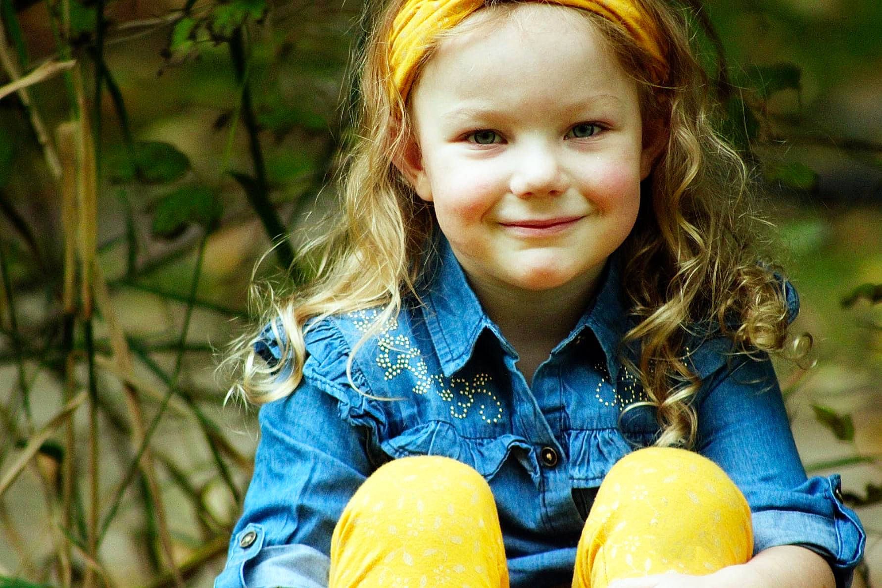 Emily joined the competition — help win amazing prizes! blond, brown_hair, child, eye, face, fun, grass, happy, iris, joy, light, people, people_in_nature, person, plant, sitting, smile, sunlight, toddler, tree