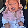 baby, infant, smiling, pink_hat, pink_bib, white_clothing, car_seat, happy, child, portrait, cute, small_hands, face, comfort, seatbelt_warning, indoors, closeup, headwear, baby_clothes, human