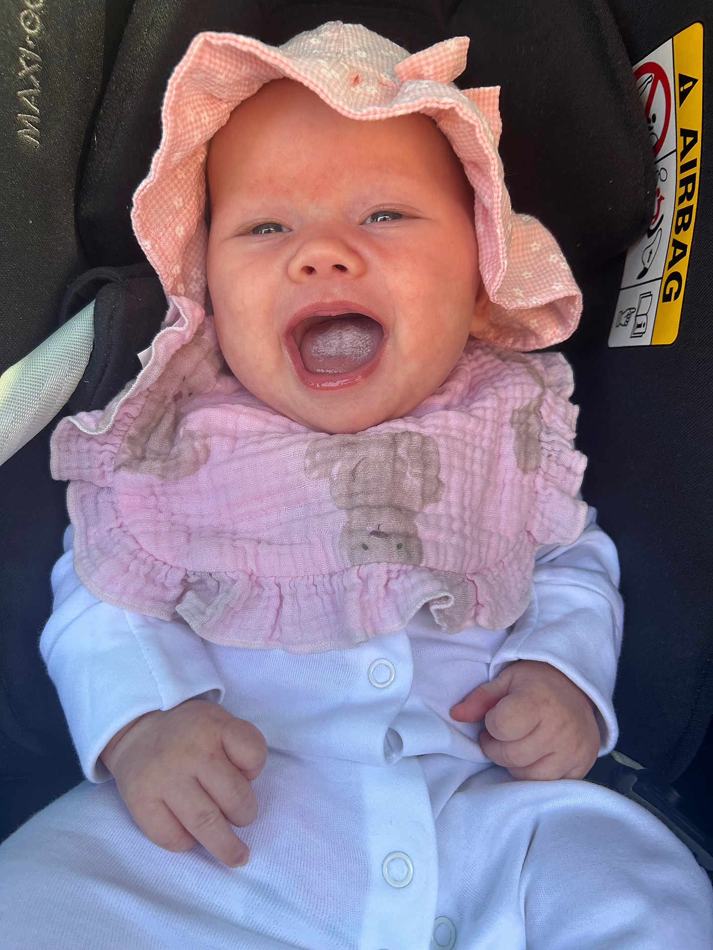 Callie joined the competition — help win amazing prizes! baby, infant, smiling, pink_hat, pink_bib, white_clothing, car_seat, happy, child, portrait, cute, small_hands, face, comfort, seatbelt_warning, indoors, closeup, headwear, baby_clothes, human