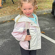 Julia participe au concours pour gagner de l'argent avec cette photo : child, girl, braids, pigtails, jacket, pink, white, backpack, smile, outdoor, parking_lot, asphalt, grass, bicycle, tree, casual_clothing, happy, standing, person, playful