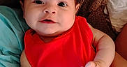 Makenzie is registered to the contest to win money with this photo: baby, infant, red_clothing, blanket, cushion, face, person, smile, skin, hand, portrait, cute, indoors, young_child, resting, expression, closeup, human, head, lying_down