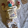 baby, infant, pacifier, blanket, pajamas, hat, wooden_sign, one_month, lying_down, cute, sleepy, child, newborn, soft_texture, yellow_clothing, white_background, foot, hand, face, portrait