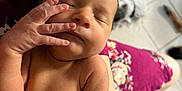 Zaeana is registered to the contest to win money with this photo: newborn, baby, sleeping, hand, face, person, arm, skin, floral_dress, watch, floor, tile, dog, blurred_background, indoor, closeup, peaceful, resting, holding, portrait