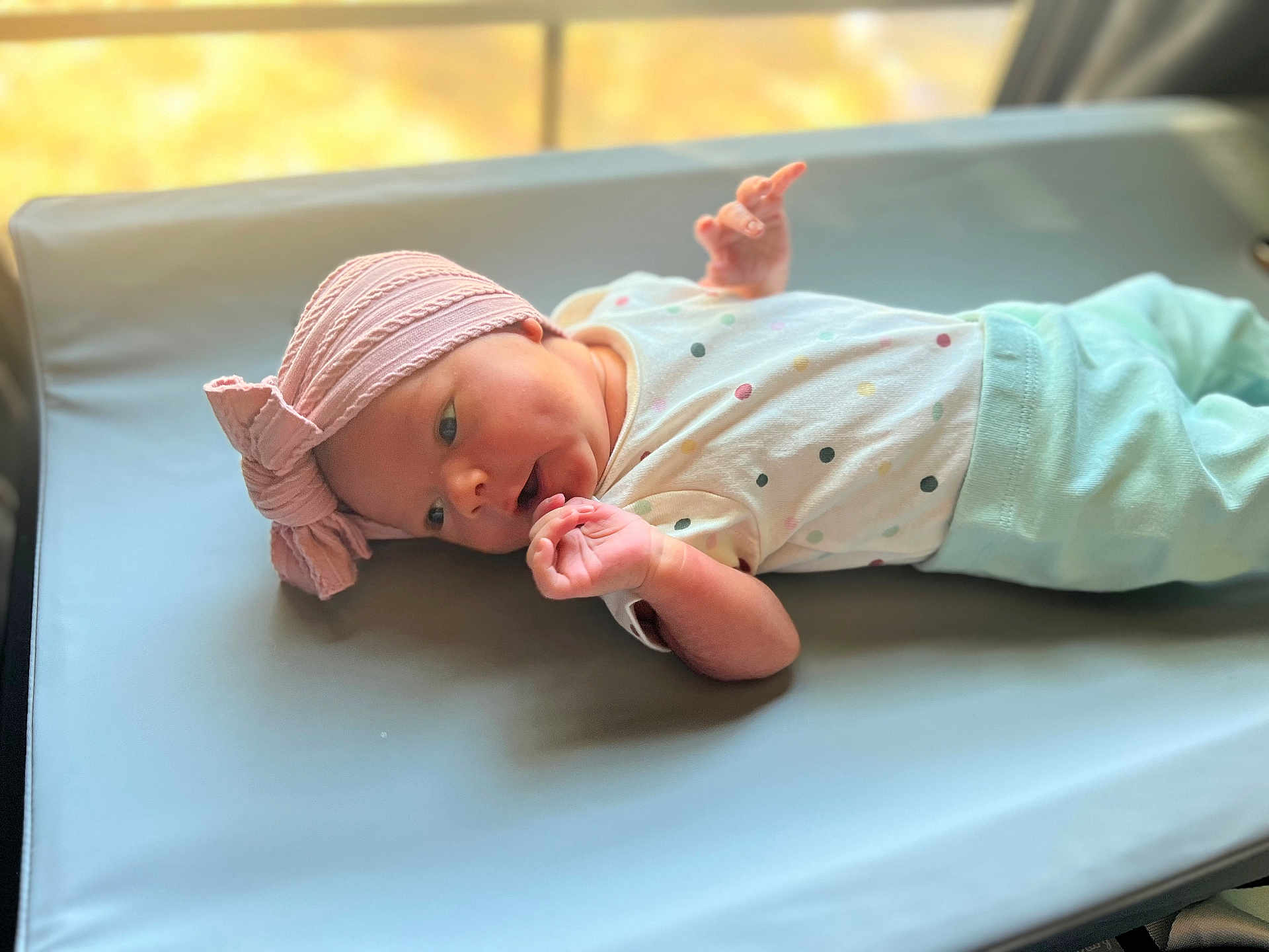 Zaeana is registered to the contest to win money with this photo: baby, infant, hat, pink, lying_down, changing_mat, clothing, polka_dots, hand, face, skin, newborn, cute, soft_light, indoors, window_light, expression, small_hands, cozy, resting