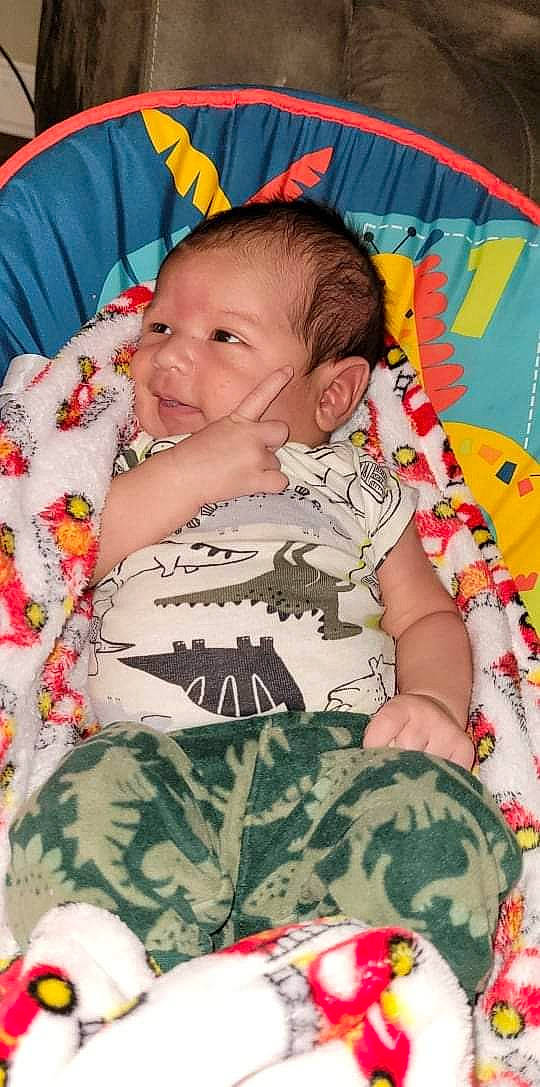 Byron is registered to the contest to win money with this photo: arm, baby, baby_toddler_clothing, camouflage, cheek, comfort, face, facial_expression, finger, hairstyle, head, military_camouflage, organ, person, pink, product, skin, sleeve, smile, textile