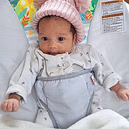 Vaÿna a rejoint le concours — aidez-le/la à gagner de superbes lots ! baby, infant, hat, pink_hat, pom_poms, onesie, blanket, baby_seat, animal_print, giraffe, sloth, bird, indoor, cute, child, face, hands, clothing, comfort, resting