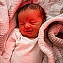 baby, newborn, infant, smile, sleeping, blanket, soft_texture, pink, gray, white_clothing, cozy, closeup, peaceful, portrait, child, human, cute, resting, warm_light, indoor