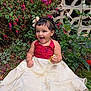 child, toddler, smiling, dress, grass, flower, greenery, outdoor, happy, candy, headband, nature, person, portrait, sitting, garden, cute, young, celebration, fun