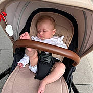 Laura is registered to the contest to win money with this photo: baby, stroller, sleeping, infant, sidewalk, urban, foot, leg, clothing, safety_belt, beige, outdoor, peaceful, child, person, baby_clothes, hand, head, seat, transport
