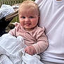 Laura is registered to the contest to win money with this photo: baby, child, infant, person, face, blue_eyes, tongue_out, blanket, pink_clothing, sleeves, hand, lap, white_shirt, outdoor, wooden_fence, stroller, happy, cute, smile, skin
