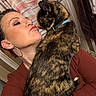 Luna is registered to the contest to win money with this photo: woman, cat, tortoiseshell_cat, indoor, affection, face, earrings, collar, shoulder, curtain, makeup, long_sleeve, jewelry, pet, closeup, human, animal, love, interaction, portrait