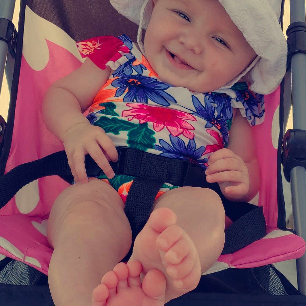 Tinley is registered to the contest to win money with this photo: arm, baby, baby_products, cheek, child, finger, foot, footwear, hand, headgear, headwear, human_body, human_leg, joy, leg, person, pink, product, skin, smile