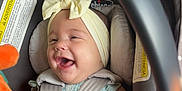 Aaliyah joined the competition — help win amazing prizes! baby, bow, car_interior, car_seat, child, clothing, cute, face, hand, happy, headband, indoors, infant, orange, person, playful, safety_strap, seatbelt, smiling, toy