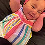 baby, child, smiling, headband, pink, dress, striped, colorful, arms, lying_down, closeup, infant, cute, face, happy, person, clothing, indoors, playful, young