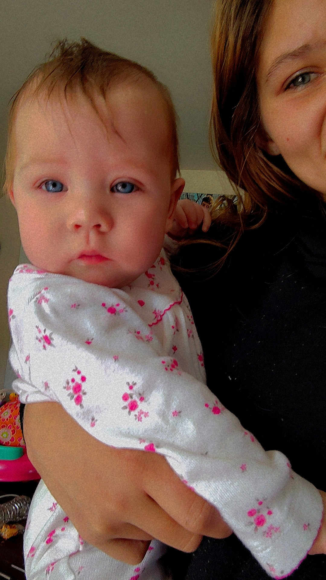 Stormy joined the competition — help win amazing prizes! baby, child, infant, person, face, blue_eyes, white_clothing, pink_flowers, hand, holding, adult, portrait, indoor, hair, skin, looking_at_camera, close_up, calm, curious, toddler