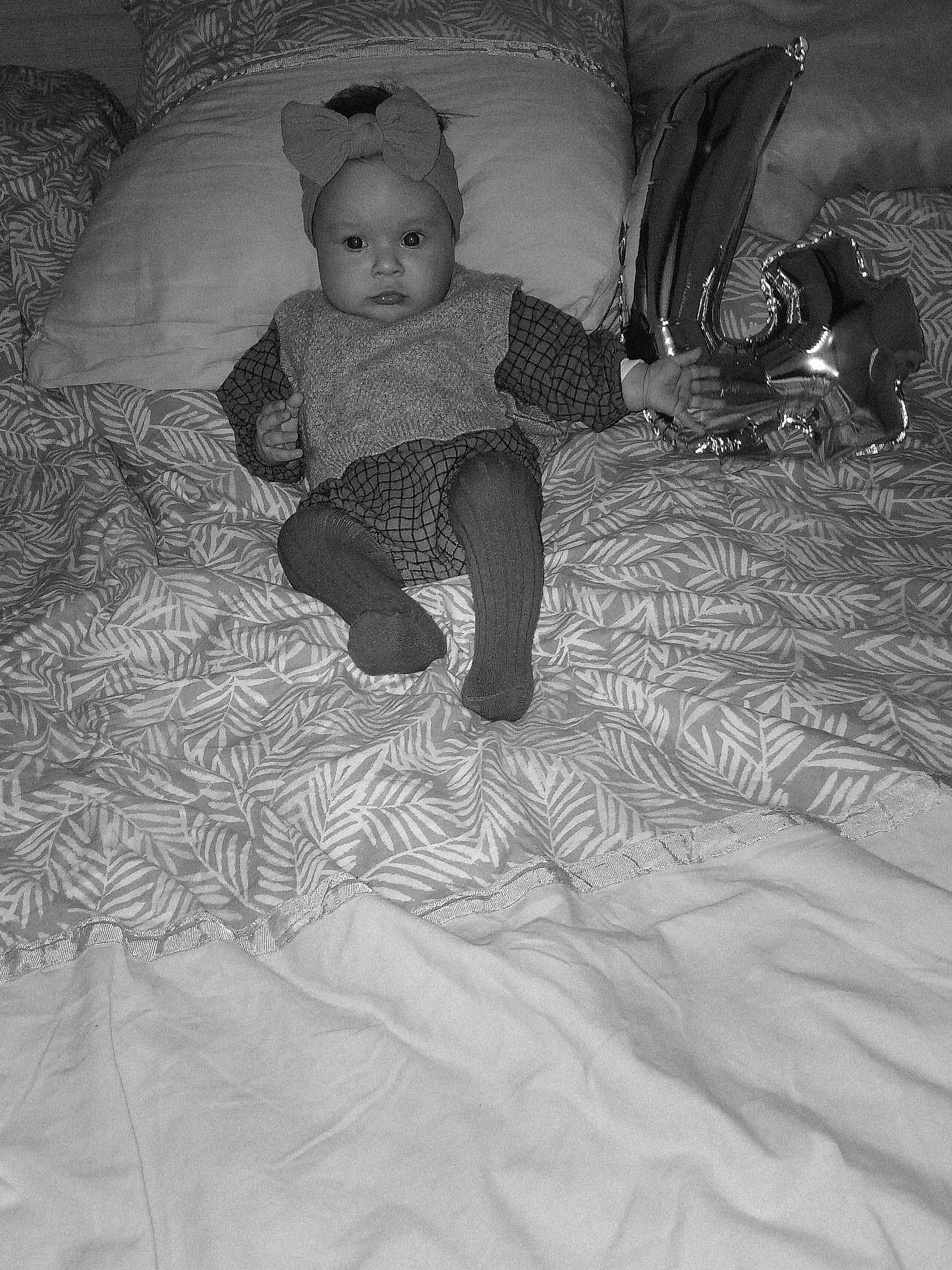 Hosanna a rejoint le concours — aidez-le/la à gagner de superbes lots ! baby, child, bed, pillow, blanket, balloon, number_balloon, headband, bow, clothing, pattern, indoor, portrait, sitting, infant, cute, monochrome, decor, person, soft_lighting