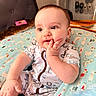 baby, child, infant, portrait, face, eyes, smiling, happy, sitting, hand, fingers, onesie, clothing, cushion, blanket, animal_pattern, indoor, home, furniture, photography