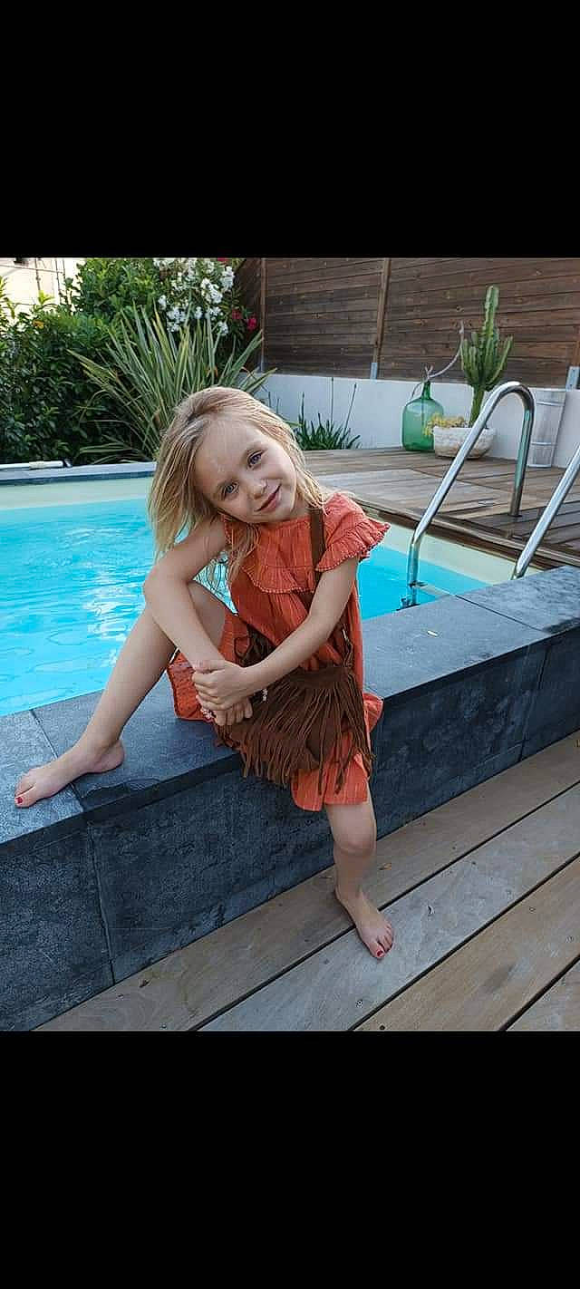 Maëlys participe au concours pour gagner de l'argent avec cette photo : barefoot, child, dress, fawn, flooring, foot, fun, grass, green, happy, human_leg, joy, leisure, person, plant, smile, summer, swimming_pool, thigh, tree