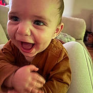 Kanen joined the competition — help win amazing prizes! baby, child, smiling, happy, clapping, indoor, person, face, eyes, hands, sitting, clothing, brown_shirt, lap, home, furniture, couch, infant, cute, joyful