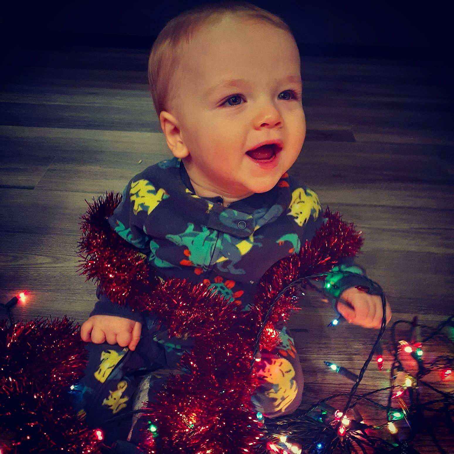 Gavin is registered to the contest to win money with this photo: baby, cheek, child, christmas, christmas_eve, christmas_lights, christmas_ornament, christmas_tree, cloud, cool, event, eye, face, happy, head, holiday, night, person, sky, toddler