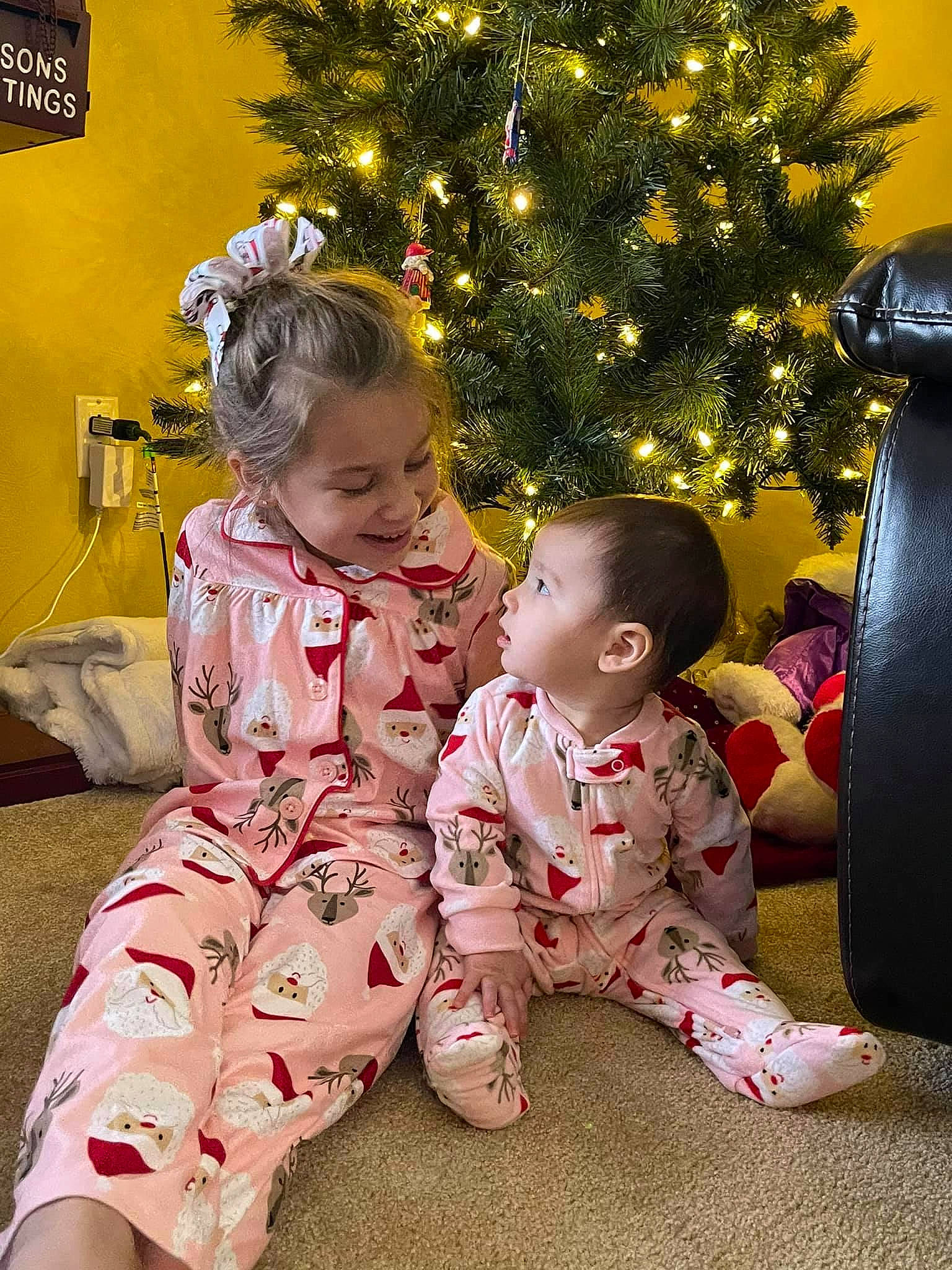 Mia is registered to the contest to win money with this photo: baby, baby_toddler_clothing, child, christmas, christmas_decoration, christmas_eve, christmas_lights, christmas_ornament, christmas_tree, holiday, holiday_ornament, human, human_body, interior_design, joy, mouth, nose, ornament, pajamas, person