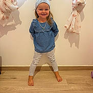 Léna a rejoint le concours — aidez-le/la à gagner de superbes lots ! barefoot, blue_top, casual_clothing, child, curtains, girl, happy, indoor, necklace, person, pose, shadow, smiling, standing, striped_headband, striped_leggings, tied_curtains, wall, wooden_floor, young