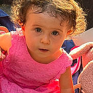 Inès a rejoint le concours — aidez-le/la à gagner de superbes lots ! toddler, child, curly_hair, pink_dress, sunlight, portrait, cute, baby, innocent, face, expression, indoors, soft_toys, blanket, young_child, closeup, person, summer, casual, warm_light