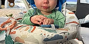 Silas is registered to the contest to win money with this photo: baby, blue_hat, green_pajamas, baby_seat, toy, indoor, child, cute, infant, playtime, smiling, face, hands, carpet, decor, nutcracker, plush_toy, furniture, expression, person