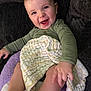 Silas joined the competition — help win amazing prizes! baby, smiling, blanket, couch, infant, child, happy, face, person, clothing, long_sleeve, indoors, cute, skin, head, eyes, mouth, hand, sitting, comfort