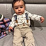 baby, child, sitting, couch, suspenders, pants, shirt, cute, indoors, face, foot, hair, expression, clothing, person, infant, portrait, home, plaid_blanket, curious