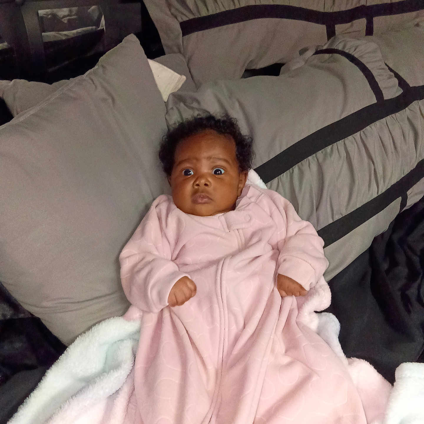 Charming joined the competition — help win amazing prizes! baby, infant, pink_onesie, blanket, pillow, bed, sleepwear, cute, wide_eyes, indoor, soft_texture, cozy, child, person, portrait, resting, expression, young, warm, comfort
