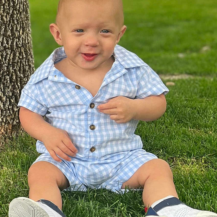 Cam is registered to the contest to win money with this photo: boy, child, clothing, face, footwear, grass, head, lawn, male, pants, person, photography, plant, portrait, shirt, shoe, shorts, sitting, sneaker, tree