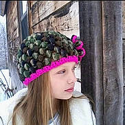 Grace is registered to the contest to win money with this photo: child, girl, knit_hat, winter, snow, wooden_cabin, window, outdoor, cold, pensive, portrait, face, long_hair, warm_clothing, nature, tree, seasonal, scenery, frost, profile