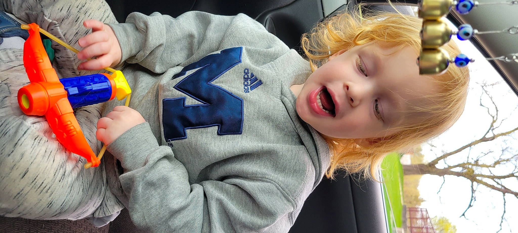 Willie is registered to the contest to win money with this photo: baby_toddler_clothing, cheek, child, fun, gesture, grass, happy, laugh, nail, person, portrait_photography, sitting, sleeve, smile, thumb, toddler, toy, wrist