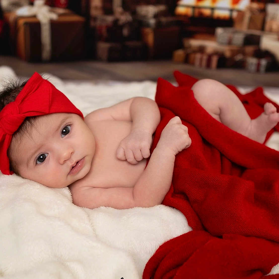 Sofia joined the competition — help win amazing prizes! baby, blanket, child, cozy, cute, face, gifts, headwear, holiday, indoors, infant, lying_down, newborn, portrait, red_blanket, red_bow, skin, soft_texture, white_blanket, wrapped_presents
