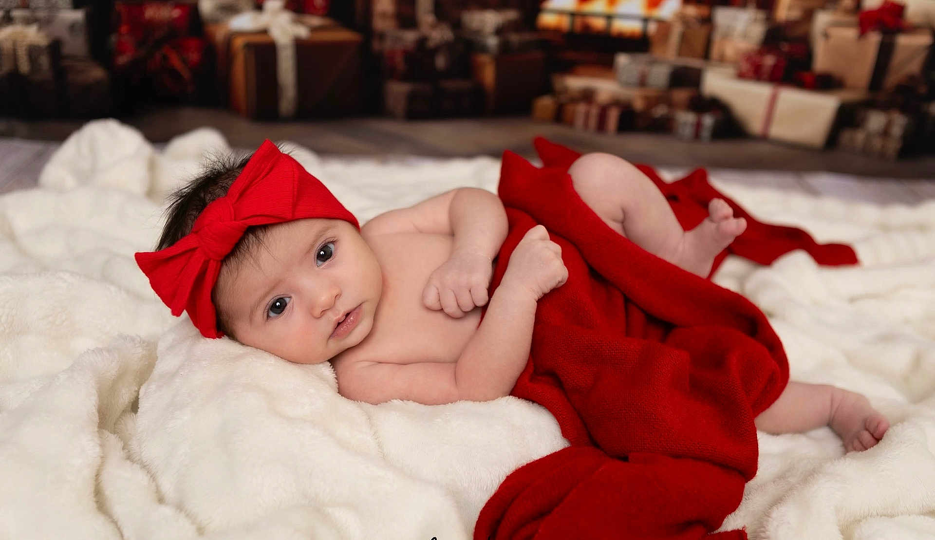 Sofia joined the competition — help win amazing prizes! baby, infant, red_bow, red_blanket, white_blanket, portrait, indoors, holiday, gifts, wrapped_presents, cute, lying_down, soft_texture, cozy, newborn, child, face, skin, headwear, blanket