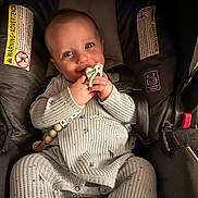 Kody is registered to the contest to win money with this photo: baby, baby_toy, car_seat, child, closeup, clothing, cute, hands, happy, indoor, infant, onesie, pacifier, person, portrait, safety, seat, seatbelt, smiling, warning_label