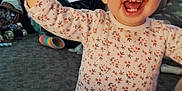 Tehleyiah is registered to the contest to win money with this photo: toddler, child, smiling, happy, pajamas, floral_pattern, indoor, carpet, toy, clutter, person, face, cute, baby, standing, home, living_room, furniture, playful, expression